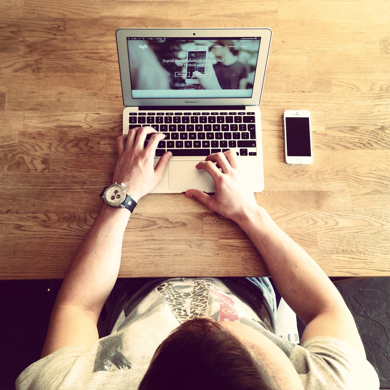 Person working on a laptop at a wooden desk